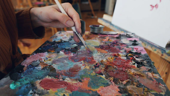 Someone is mixing paints on an artist's palette.