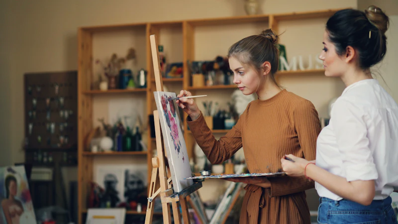 Professora orienta aluna durante pintura em ateliê de arte