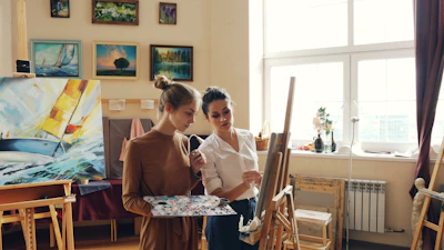 Artist instructs a student in a bright art studio.
