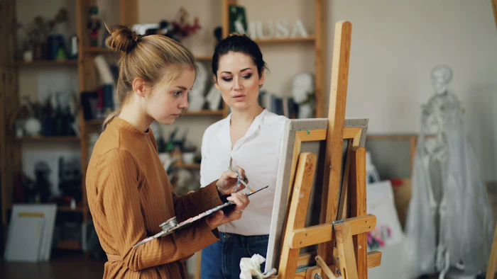 A young person and an artist talking about a painting in a studio