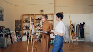 Two women are discussing a painting in a studio.