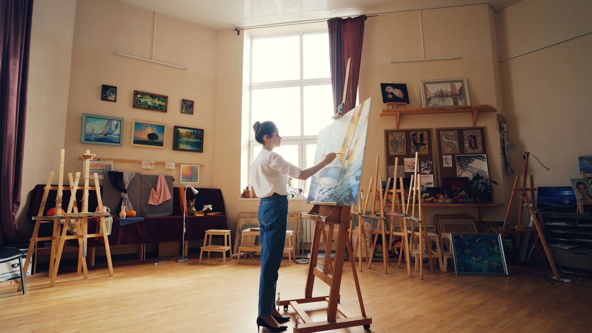An artist paints in a bright and airy studio.