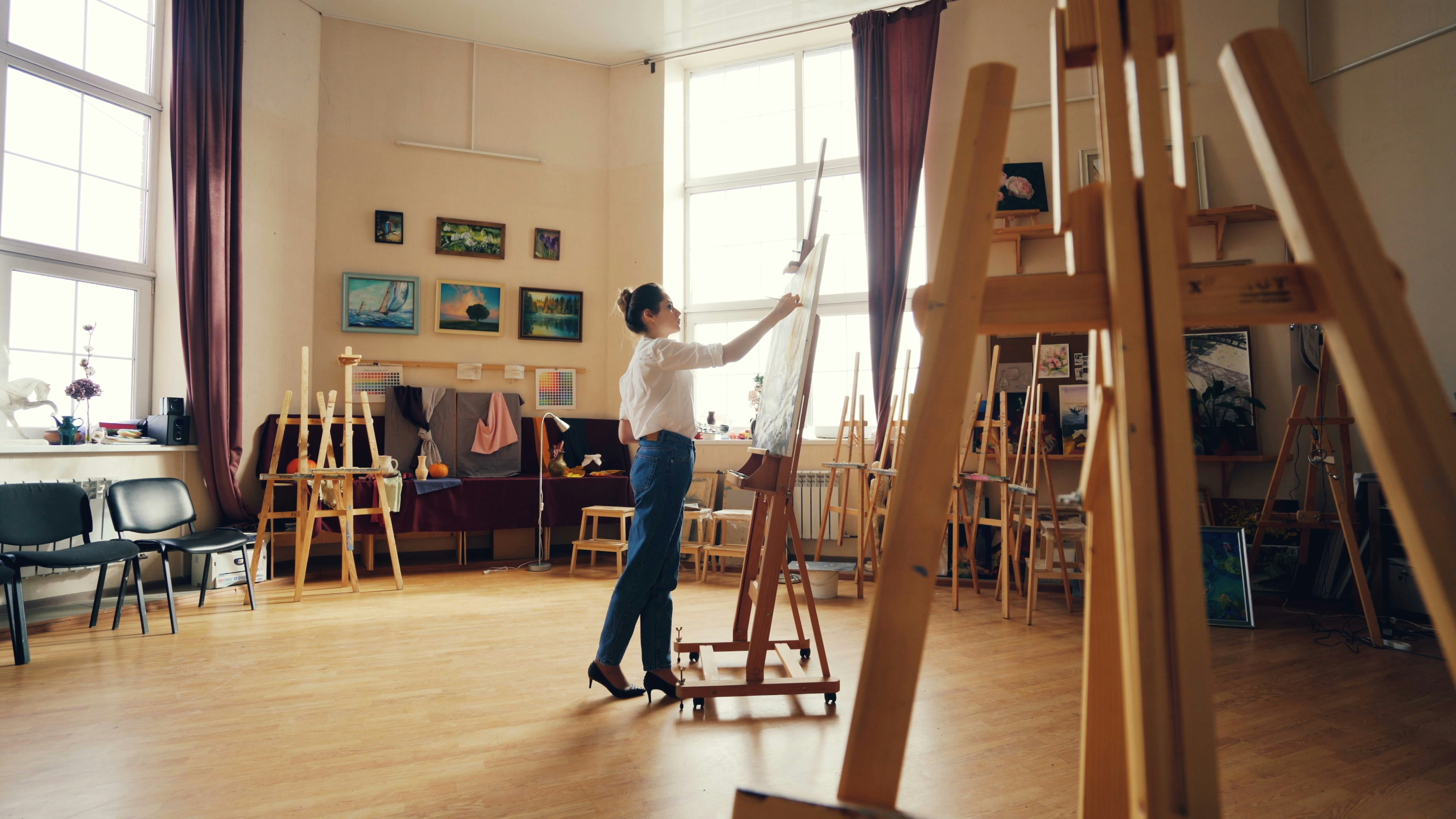 An artist is painting in a bright studio.