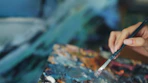 An artist mixes paint on a colorful palette.