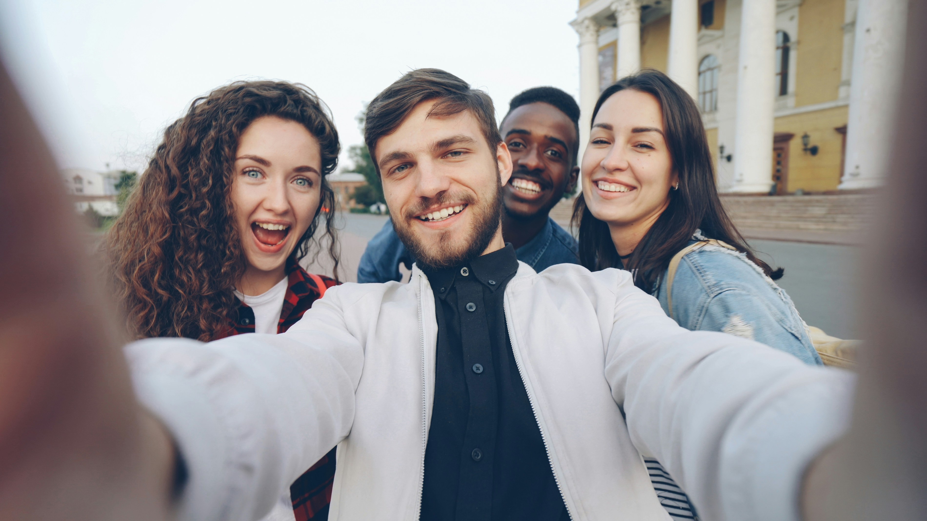 Four friends smile while taking a selfie.
