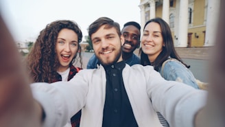 Four friends smile while taking a selfie.