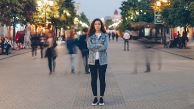 A woman standing still on a city sidewalk, gazing into the distance amid a crowd