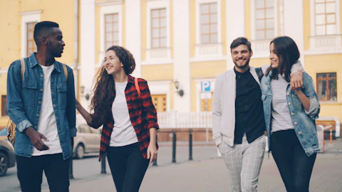 Friends are walking and smiling together outdoors.