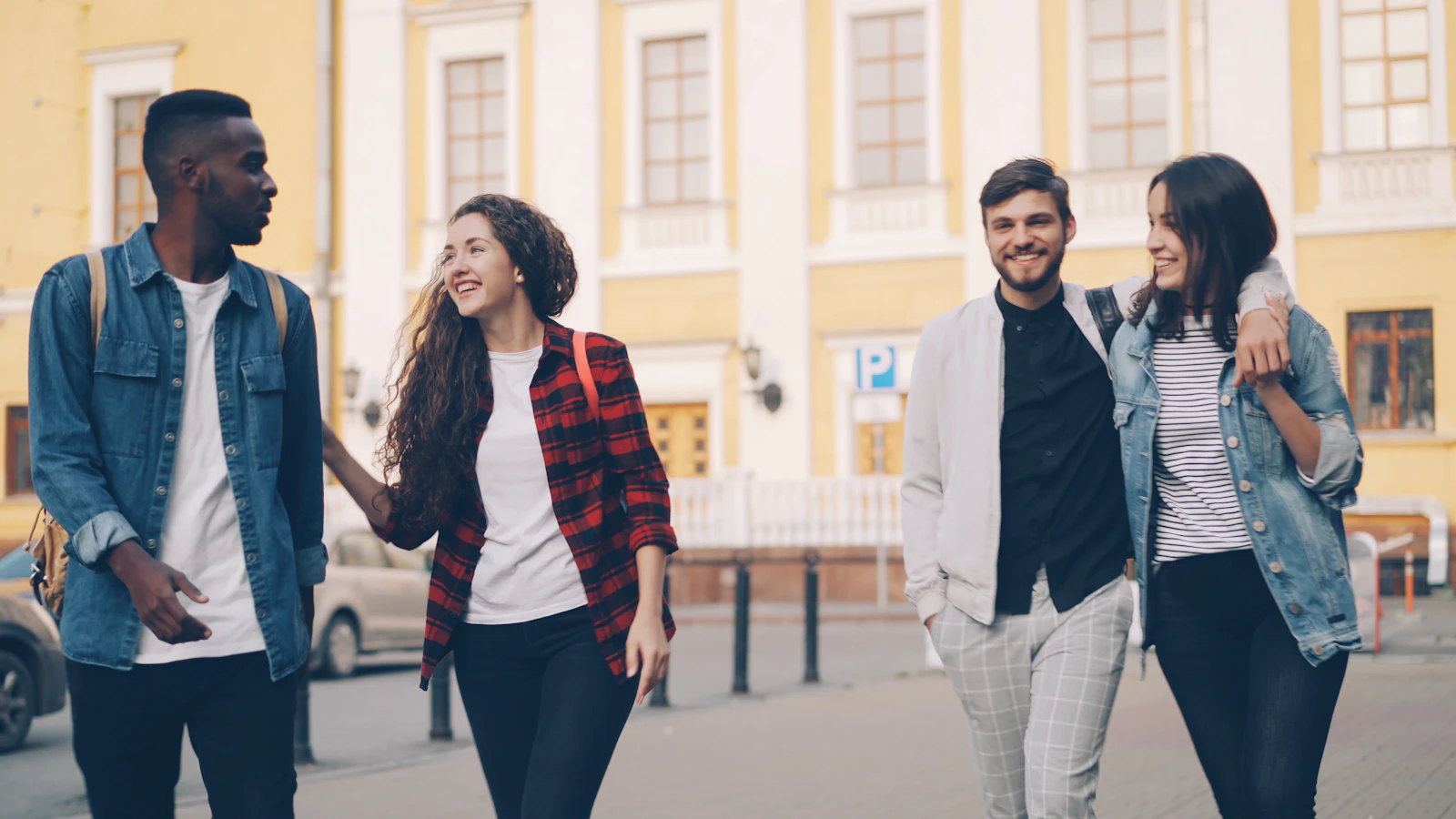 A group of friends traveling together, walking through a city with backpacks and smiling on a summer day