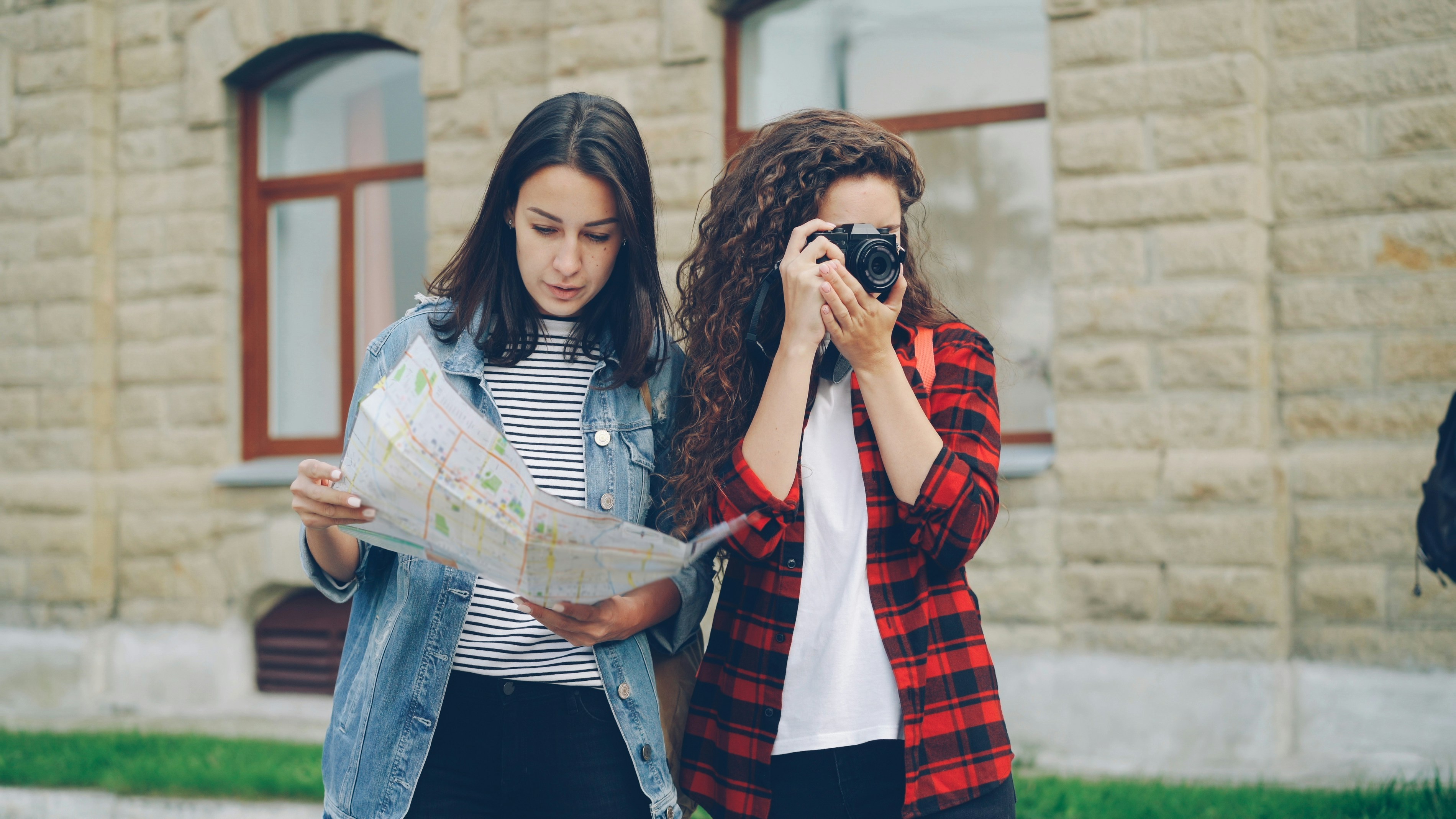 Female tourist taking photos while friend looks at map