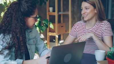 Two women work together on a laptop.