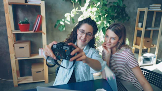 Two women are taking a selfie with a camera.
