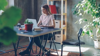 Woman works on laptop at her desk using JobberBooks bookkeeping software.