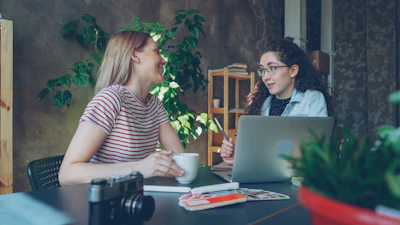 Two women discuss over a laptop