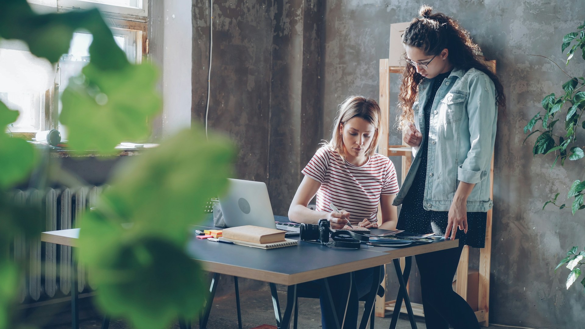 Two women work together at a desk.