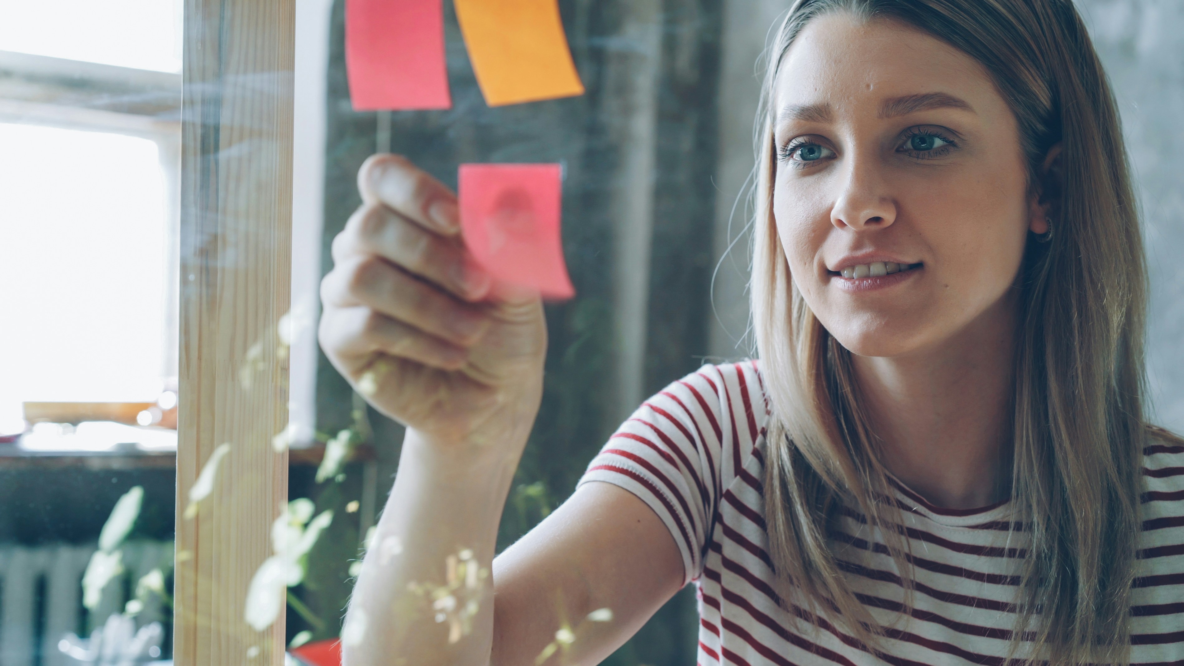 Woman posts sticky notes on glass.