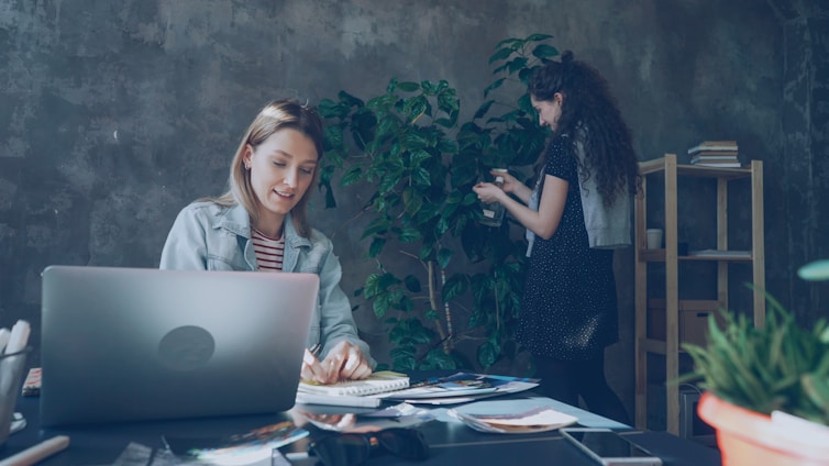 Two women work together in a enjoyable office.