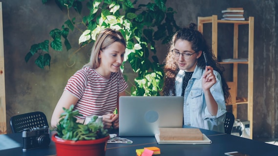 Two women collaborate at a laptop together.