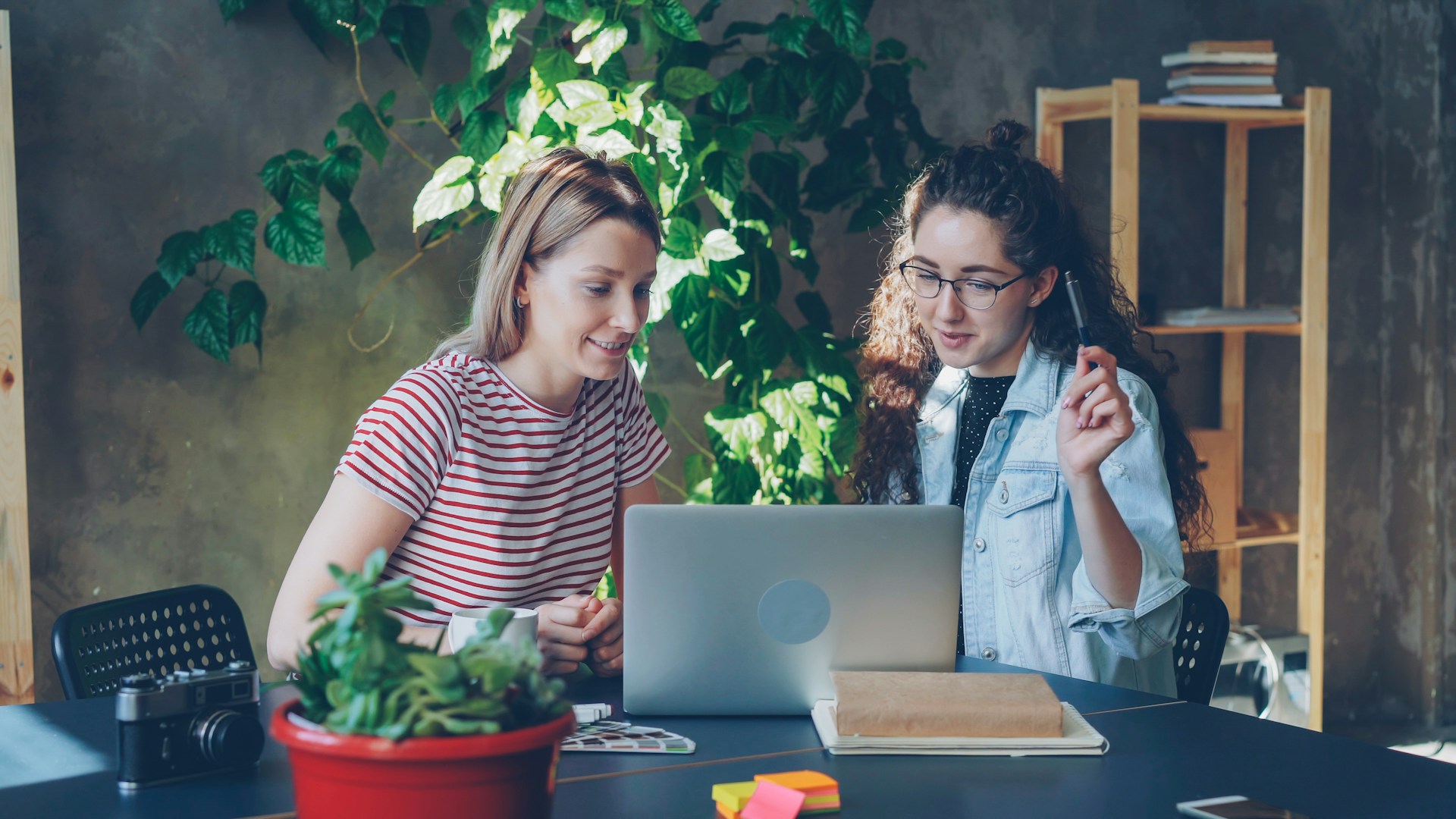 Two women collaborate at a laptop together.