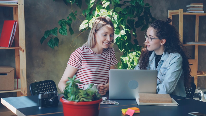 Two women work together at a laptop.