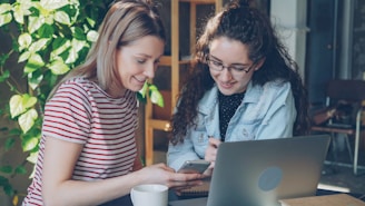 Two women collaborate on a laptop.