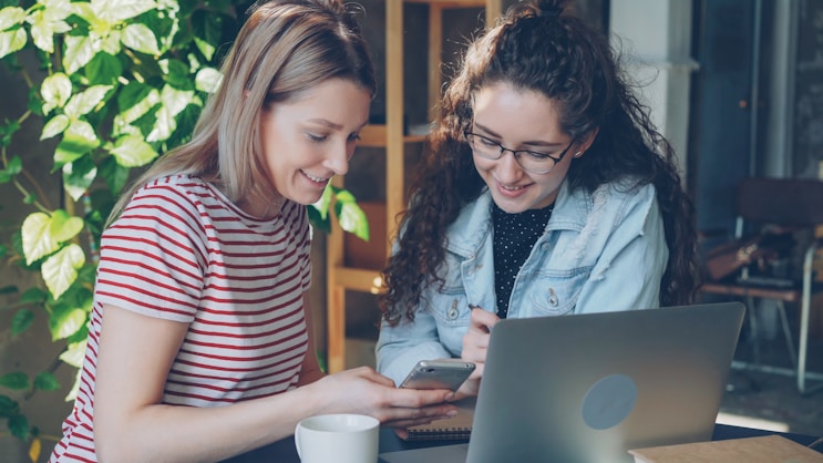 Two women collaborate on a laptop.