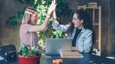 Two women celebrate success with a high five.
