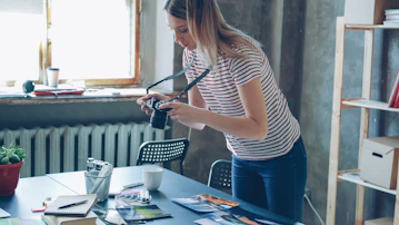 A woman is holding a camera, looking down.