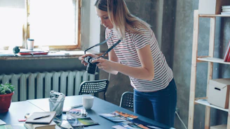 A woman is holding a camera, looking down.