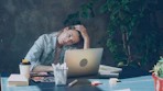 A woman appears stressed while working on laptop