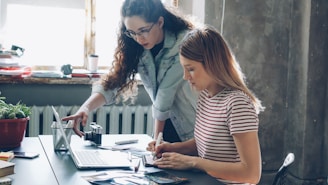 Two women work on a laptop together.