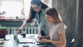 Two women work on a laptop together.