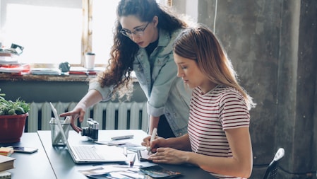 Two women work on a laptop together.