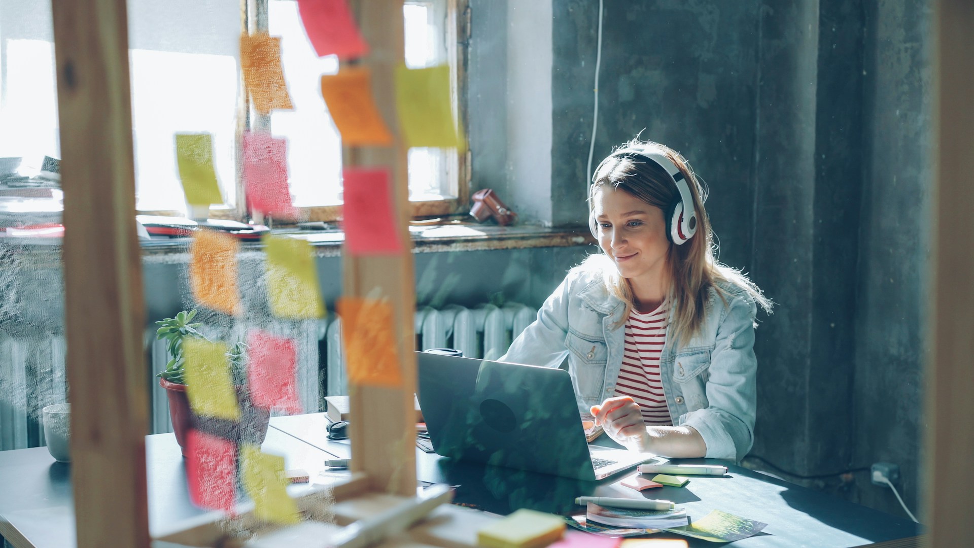 Woman working on laptop with sticky notes.