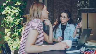 Two women are discussing something over a laptop