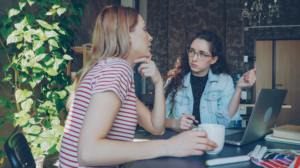 Two women are discussing something over a laptop