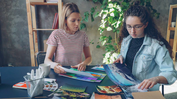 Two women are working together on artwork.