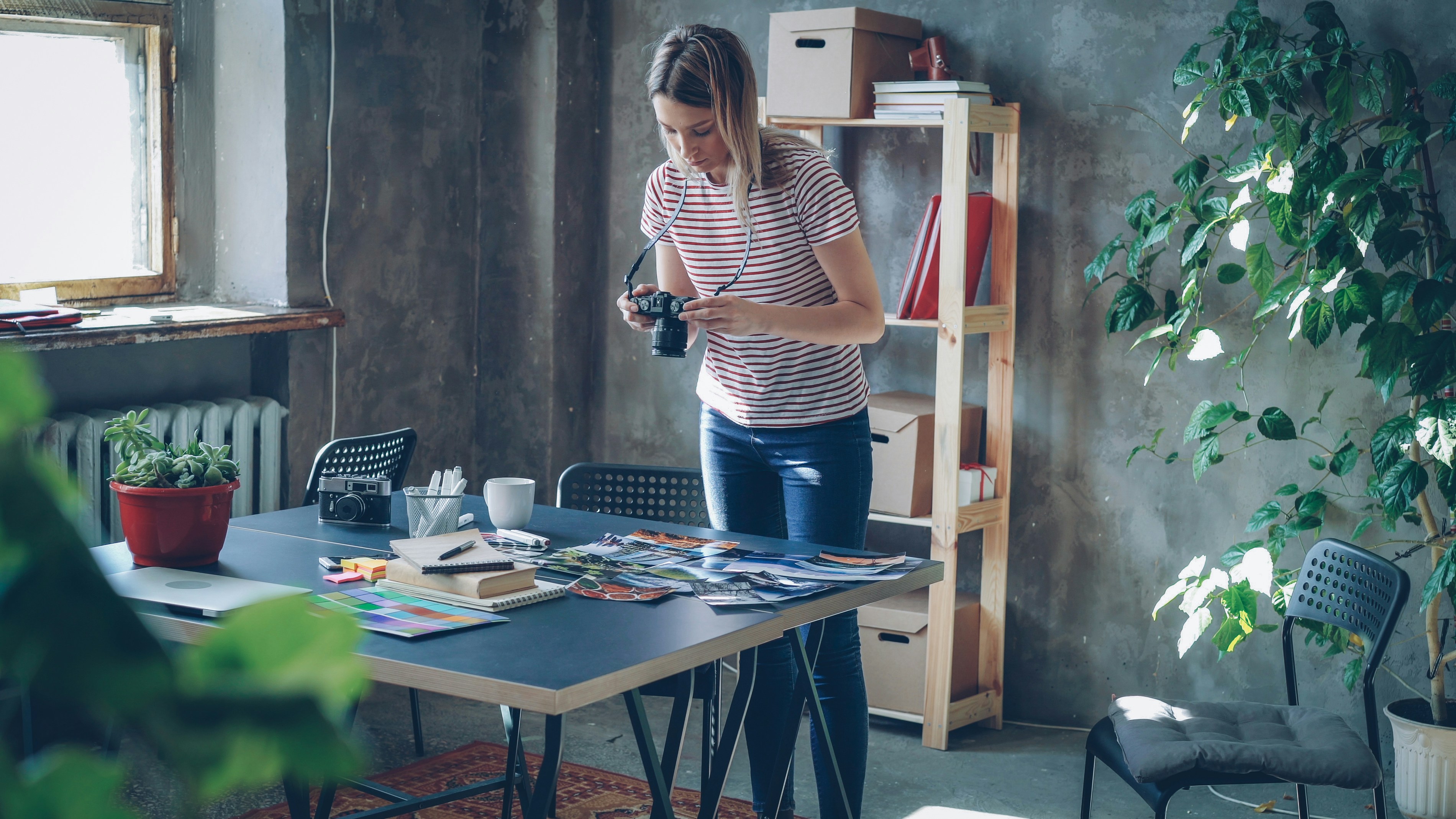 A woman is taking pictures at her work desk.