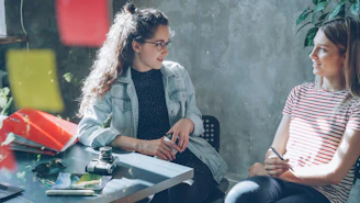 Two women are having a conversation at a table.