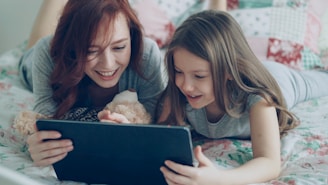 Mother and daughter watch something on a tablet.