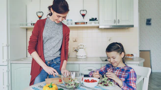 Mother and daughter prepare food together in the kitchen.