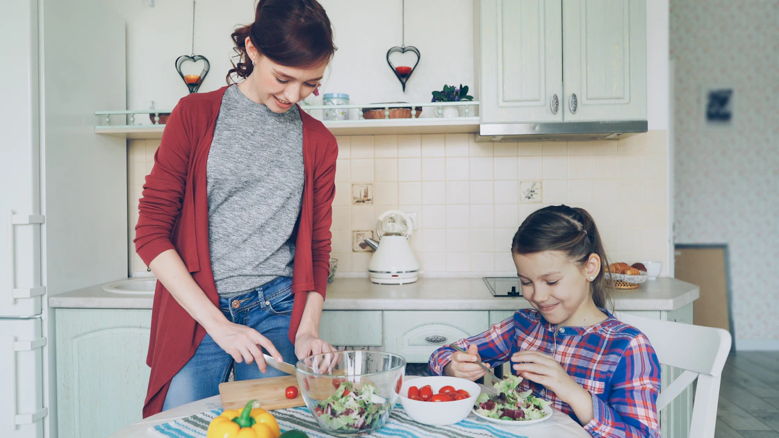 Mother and daughter prepare food together in the kitchen.