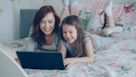 Mother and daughter laugh while using a laptop.