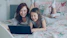 Mother and daughter laugh while using a laptop.