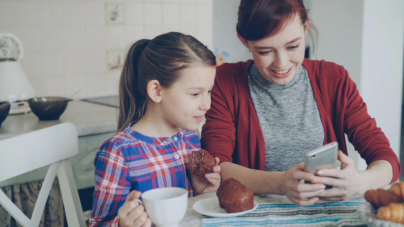 Madre e hija mirando juntas la pantalla de un teléfono móvil