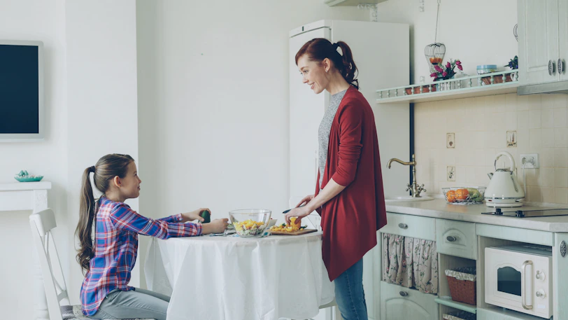 Mother serves her daughter breakfast at a table
