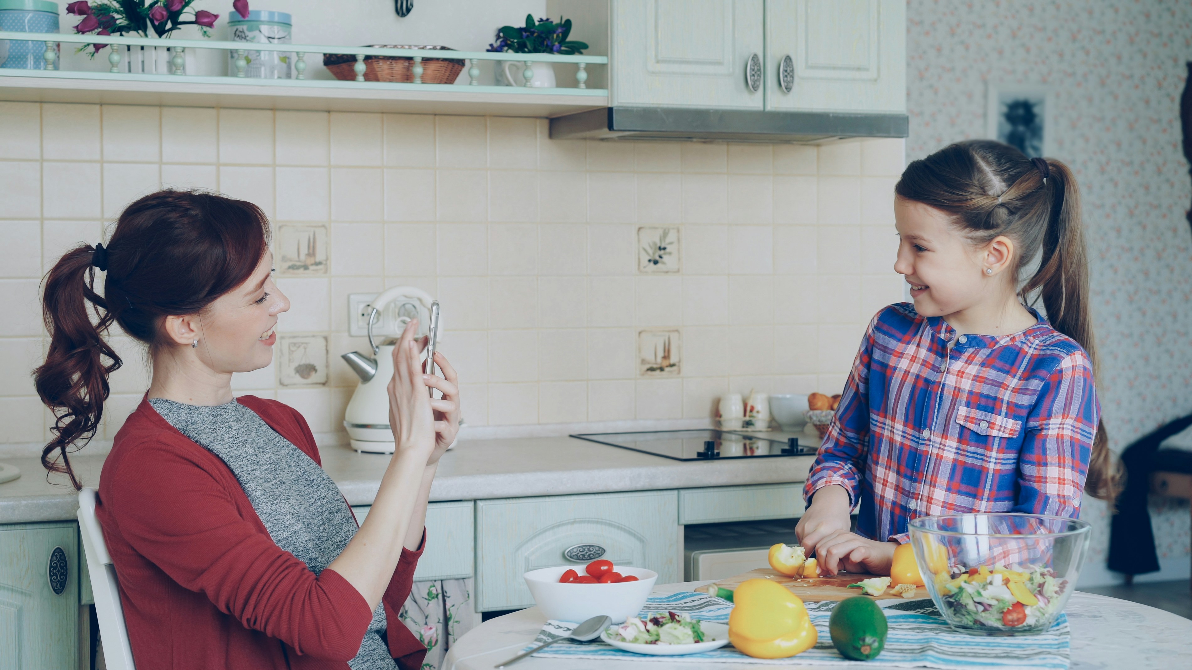 Mother taking photo of daughter cooking