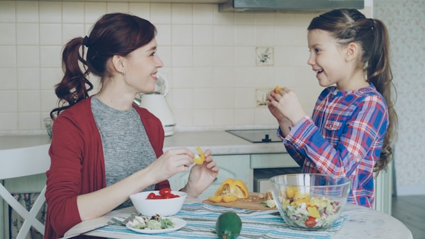 Mother and daughter prepare fruit salad together.