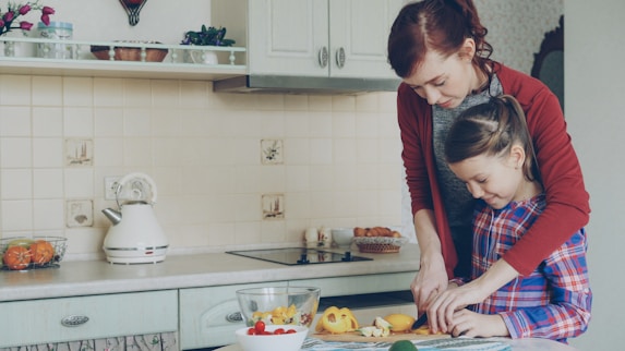 Mother and daughter cook food together in the kitchen.