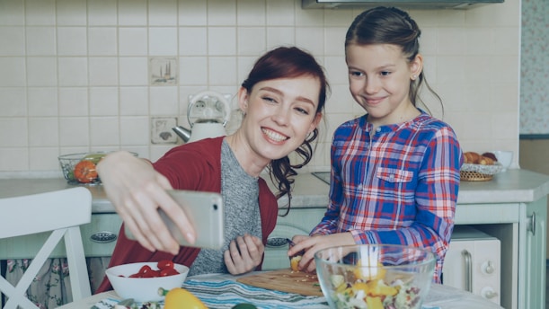 A mother and daughter take a cooking selfie.